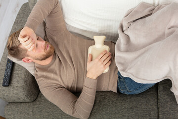 sick man lying on sofa checking his temperature at home