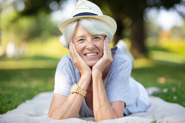happy senior woman in fitness outfit relaxing in park - obrazy, fototapety, plakaty