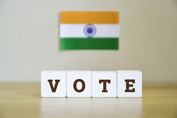 Painted wooden blocks with the inscription VOTE and flag of India in the blur background. Upcoming Indian general election, focus on the foreground.