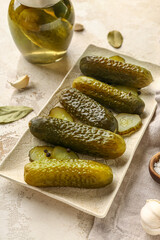 Plate with tasty canned cucumbers on beige background
