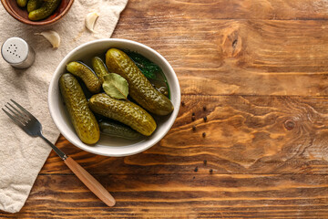 Bowl with tasty canned cucumbers on wooden background