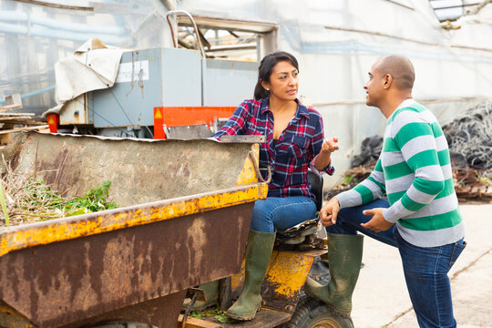 Farm workers have a dialogue next to the tractor