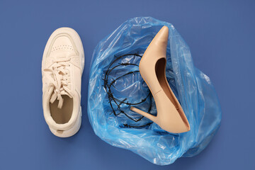 Sneaker and garbage bag with high-heeled shoe wrapped in barbed wire on blue background....