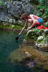 Mid Adult Female Adventurer Washing her taking Water from a Water Stream lagoon in Wilderness for Cooking