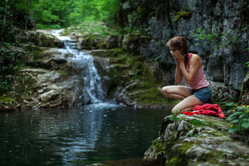 Fototapeta premium Caucasian Mid Adult Female Adventurer Washing her Face and Taking Care of Her Personal Hygiene in Outdoors Wilderness