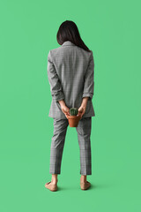 Young businesswoman with hemorrhoids and cactus on green background, back view