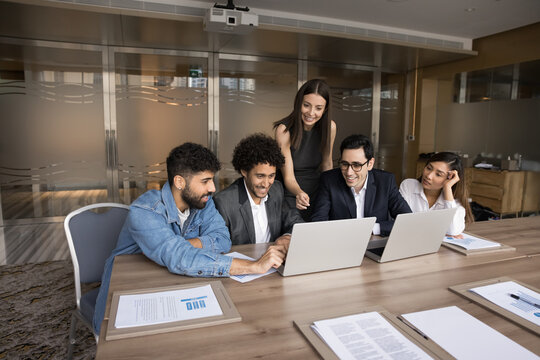 Multiethnic business team of happy colleagues using laptop for teamwork, online business communication, making group video call, watching virtual content, working on successful internet project