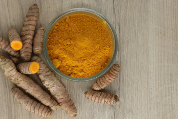 Turmeric - fresh and dried as a spice in a bowl on a wooden base