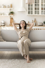 Peaceful woman rest on cozy sofa in living room with eyes closed, take deep breath fresh air,...