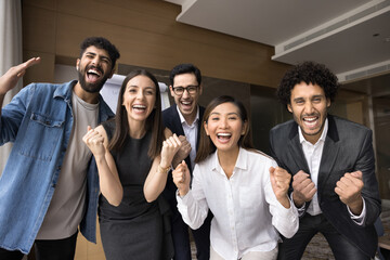 Multiethnic business team of excited project colleagues celebrating teamwork success, successful startup, making winning fist hand gestures, laughing, shouting for joy at camera - obrazy, fototapety, plakaty