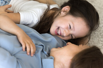 Close up shot above view of cute little laughing girl enjoy playtime with loving young mother,...
