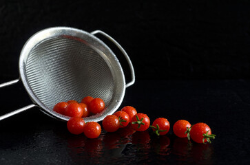 Baby Red Tomatoes with Stainless Steel Strainer on Black Background