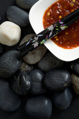 Top View of Hot Sauce in White Bowl with Dark Rocks and Japanese Chop Sticks