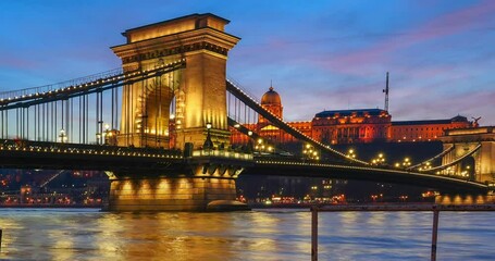 Budapest, Hungary - December 29, 2023: Beautiful sunset. Flooded Danube on the foreground. Chain bridge on the middle ground. Buda castle on the background. Time-lapse, zoom-in animation.