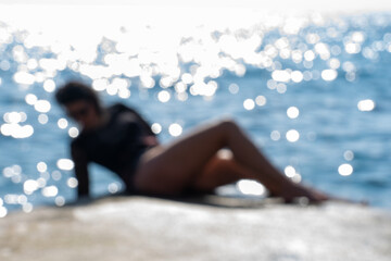 unidentifiable beautiful woman in bikini next to the sea in a sensual position. Idyllic blurred...
