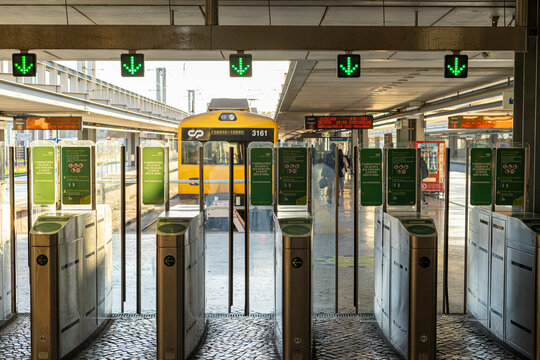 gates, or turnstiles for accessing the train at the railway station with green signs.