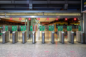 gates, or turnstiles for accessing the train at the railway station with red signs.
