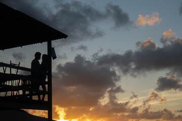 silhouette of a man and woman looking at each other, with a beautiful sunset on the beach. 