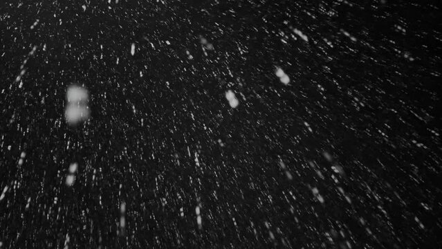 snowfall in the mountains wild nature on a dark winter night by the light of a lantern. Snowflakes spin like little stars, fly like a whirlwind, making your head spin.