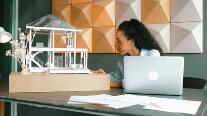 Closeup of hispanic architect hands engineer using laptop analysis house model structure. Project...