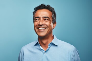 Portrait of a happy Indian man smiling at camera against blue background