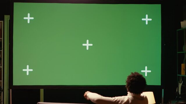 Man using streaming services on ultrawide chroma key TV to binge watch series from the comfort of his apartment. Cord cutter enjoying shows on television set during leisure time on couch