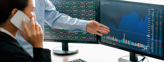 Smart cooperative male trader points the growth analysis stock market graph displayed on computer...