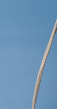 4K footage vertical video Front view SLO MO CU, Pouring fresh milk into a pitcher on a blue background.