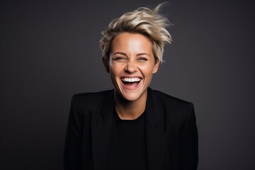 Portrait of a happy young business woman with short blonde hair over dark background