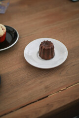 Caneles de bordeaux in white plate on wooden table. Traditional French sweet dessert serve with tea or coffee. 