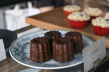 Caneles de bordeaux in white plate on wooden table. Traditional French sweet dessert serve with tea or coffee. 