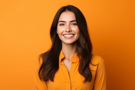 Portrait Of Beautiful Smiling Young Woman In Orange Shirt On Orange Background