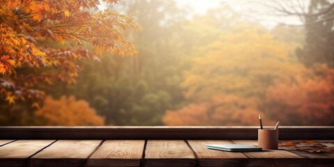 Empty wooden desk with a view of an autumn window on a sunny day.