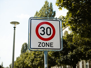 30 Zone speed limit sign in Germany. The traffic sign is located in a residential district to slow down the car drivers for safety reasons. Also it reduces air pollution in a city.