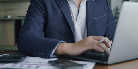 Business people working on desk with calculator, laptop and graph paper on desk..