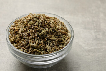 Fennel seeds in bowl on grey table, closeup. Space for text