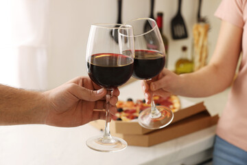 Couple clinking glasses of wine at home, closeup