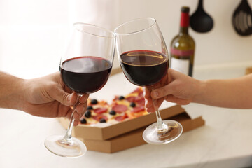 Couple clinking glasses of wine at home, closeup