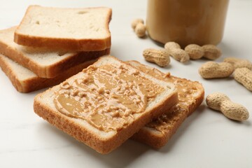 Delicious toasts with peanut butter and nuts on white table, closeup