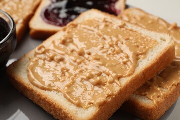 Delicious toasts with peanut butter on plate, closeup