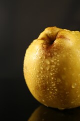 Tasty ripe quince with water drops on black background, closeup