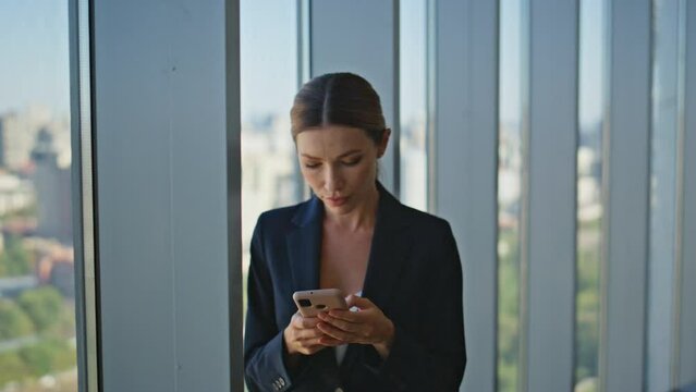 Stylish businesswoman messaging mobile phone online in modern office closeup.