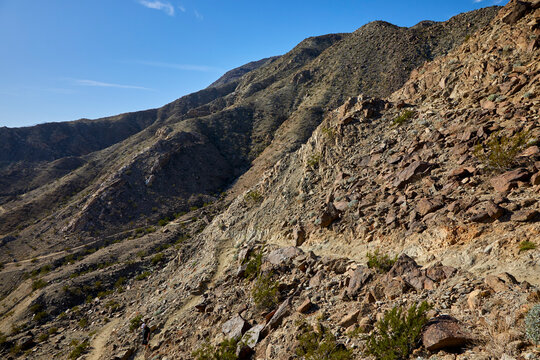 Hiking trail curving in the mountains near Palm Springs California with a blue sky and rustic landscape