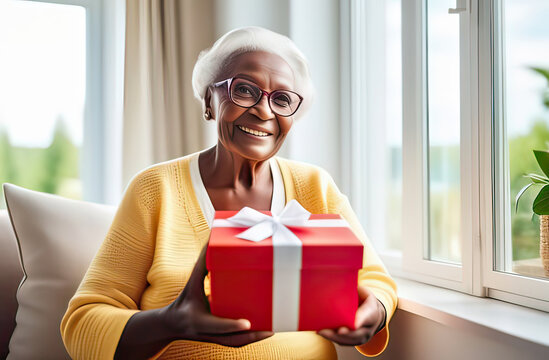 natural portrait of a senior elderly black skinned woman with a gift box, blurred home interior background