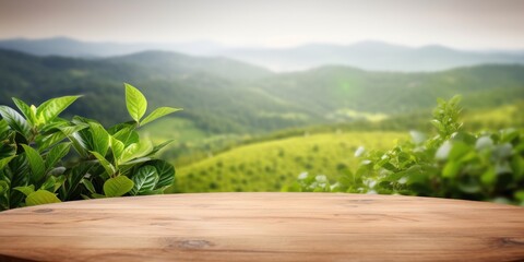 Obraz premium Circular wooden table top with blurred tea plantation landscape and green leaf frame, showcasing natural background.