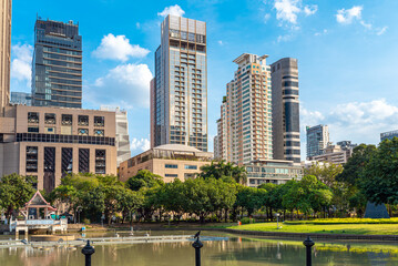 High-rise buildings at the Benchasiri Park in Bangkok. The park's facilities include a sports area and a playground, as well as numerous works of public art - obrazy, fototapety, plakaty