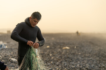 Man collecting fish from a net on the beach