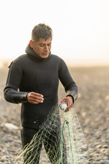 Latin fisherman in wetsuit collecting fish from a net