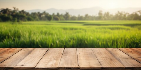 Empty wooden table with blurred morning paddy field in background for product display advertisement mock-up.
