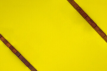右上と左下の隅にウッドキューブの赤い紐が斜めにかかった黄色い背景のフレーム